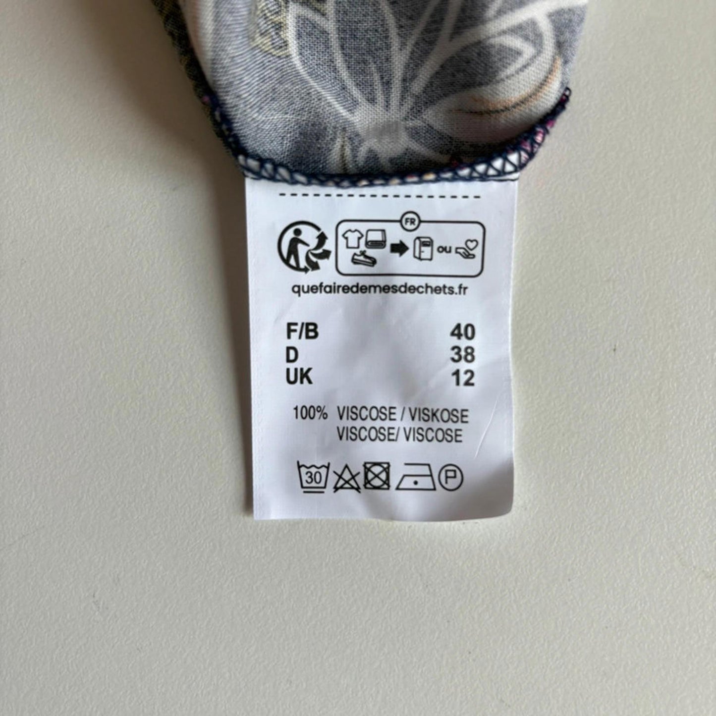 Clothing label with size and care instructions on a plain background