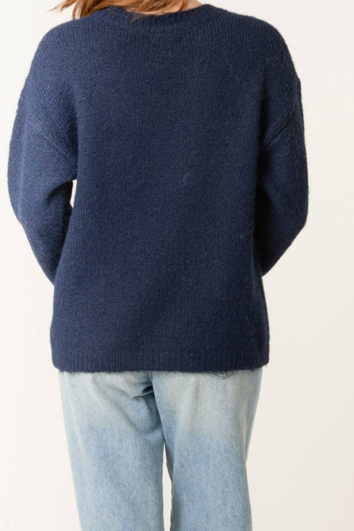 Navy sweater worn by a person on a white background