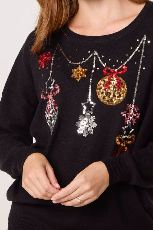 Black sweater with festive decorations including sequins and beads on a plain background