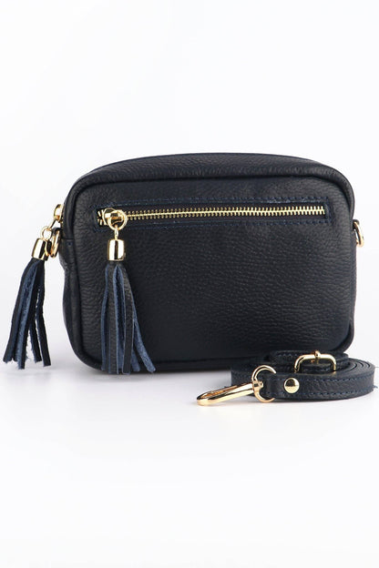 Black crossbody bag with gold accents and tassel on a white background