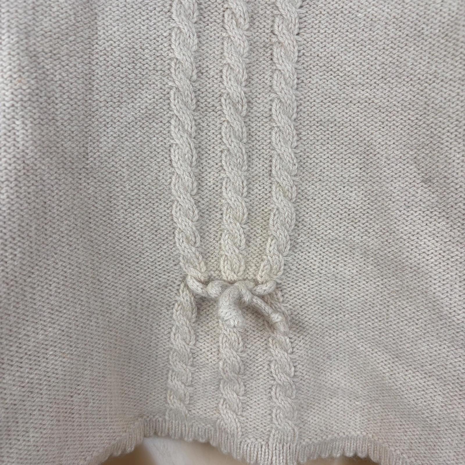 Close-up of a light pink knitted garment with a braided trim.