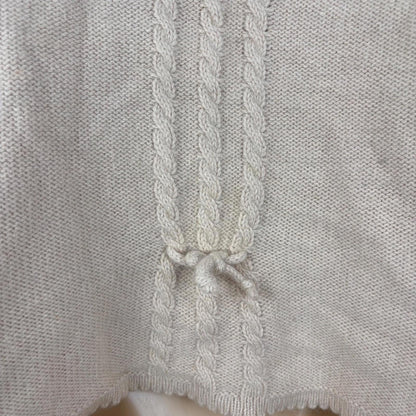 Close-up of a light pink knitted garment with a braided trim.