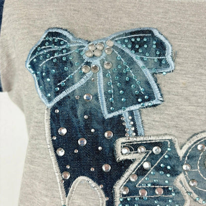 Embroidered design of a dog with a bow on a gray background