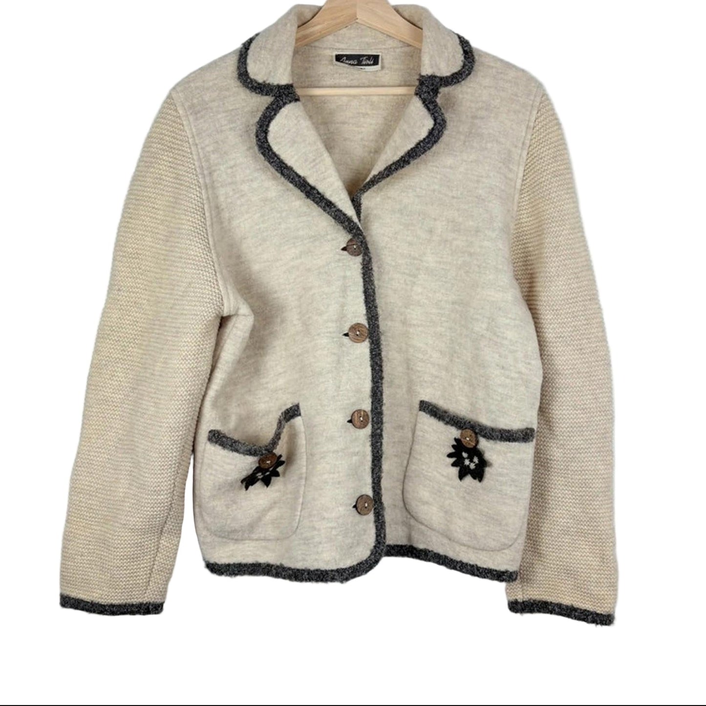 Beige jacket with dark trim on a hanger against a white background