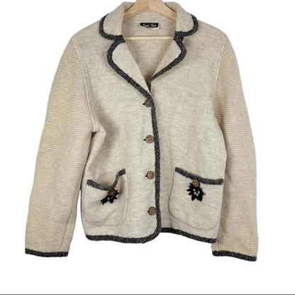 Beige jacket with dark trim on a hanger against a white background