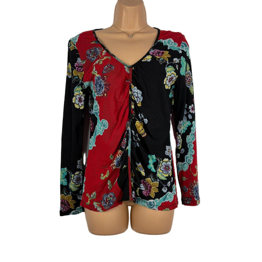 Mannequin wearing a colorful floral blouse with a red center on a white background