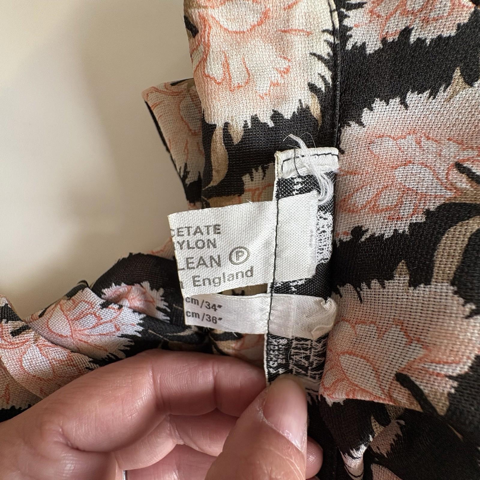 Floral-patterned fabric with a label held by a hand against a neutral background