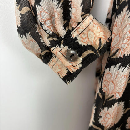 Close-up of a floral patterned shirt with a button on a white background