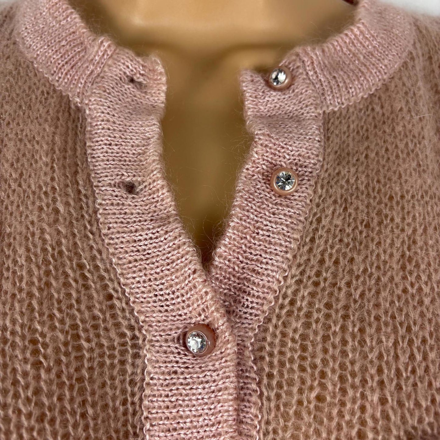 Close-up of a pink knitted cardigan with buttons on a mannequin