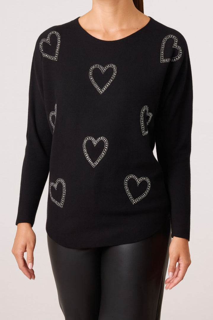 Black sweater with heart patterns on a plain background