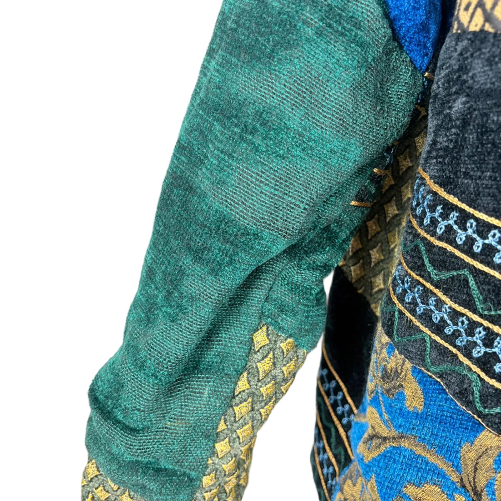 Close-up of a garment with green sleeve and blue patterned fabric on a white background