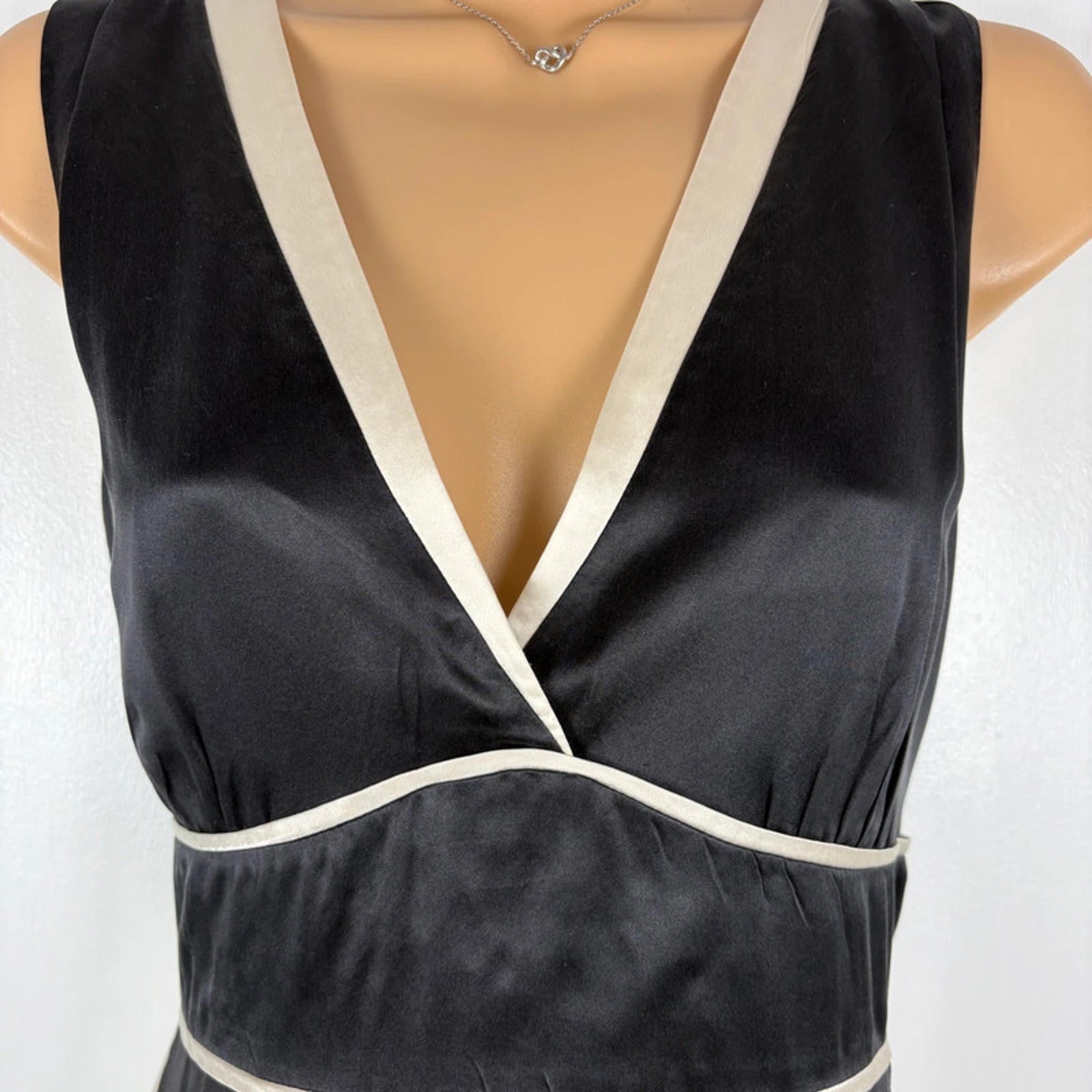 Black dress with white trim on a mannequin against a white background