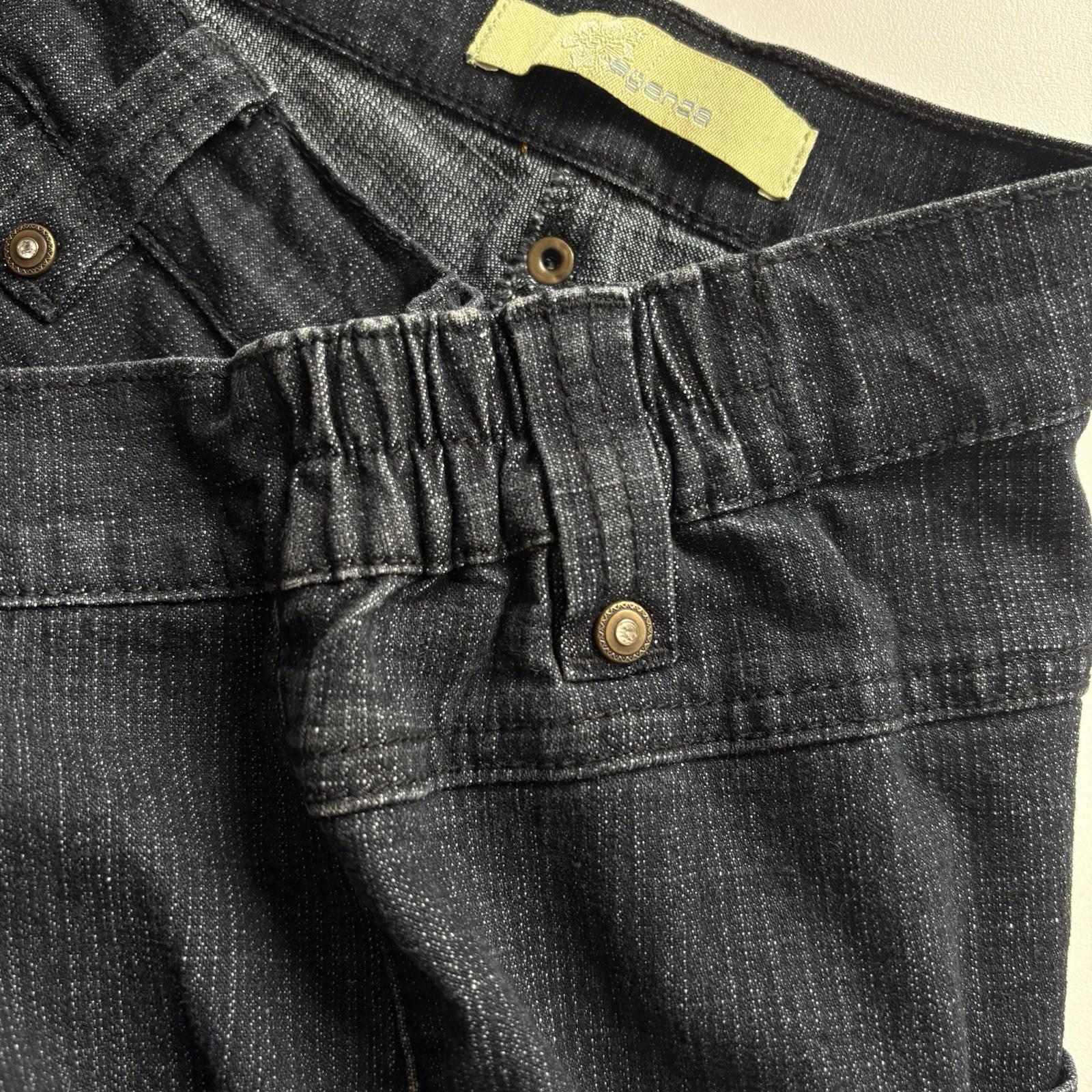 Close-up of dark denim jeans with a brand tag on a beige background