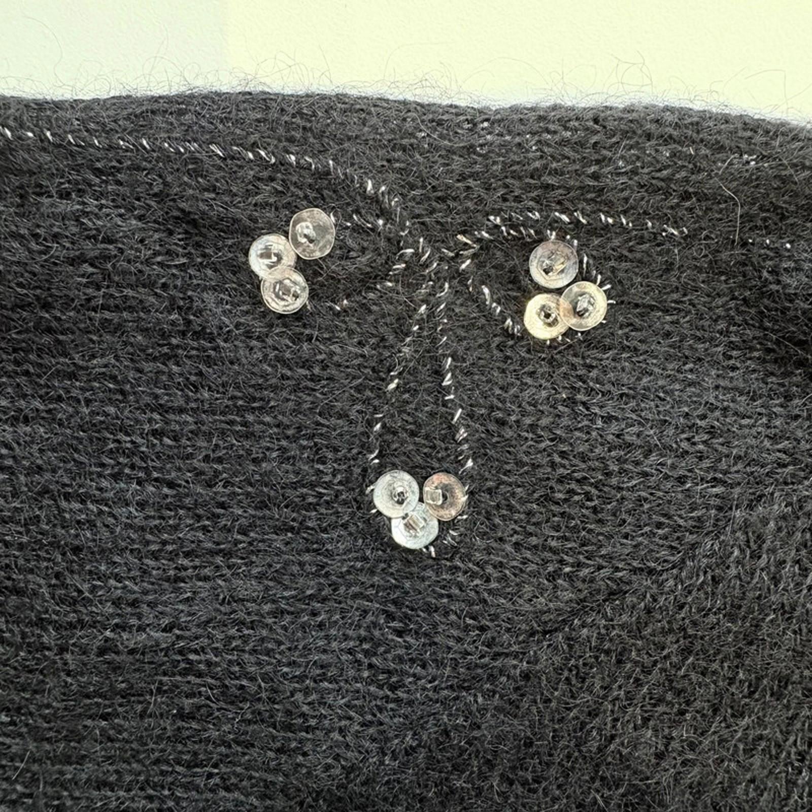 Close-up of a textured black fabric with decorative buttons and stitching.