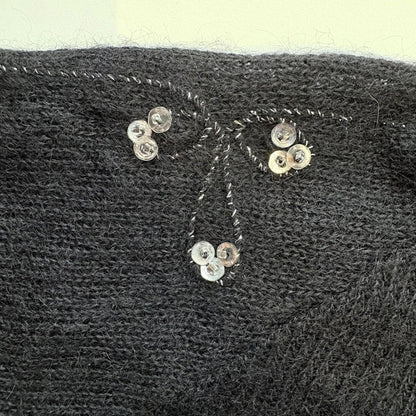 Close-up of a textured black fabric with decorative buttons and stitching.