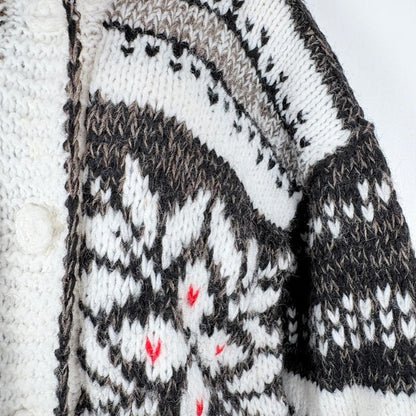 Close-up of a knitted garment with a pattern featuring black, white, and red colors.