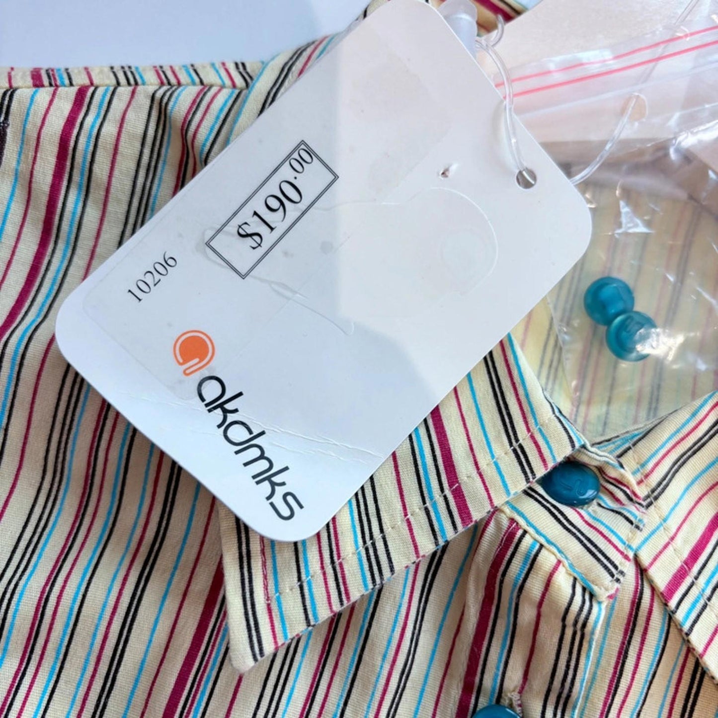 Striped shirt with a brand tag displaying 'akdmks' and original price $190.00'.