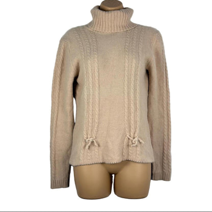 Pink cable knit sweater on a mannequin against a white background