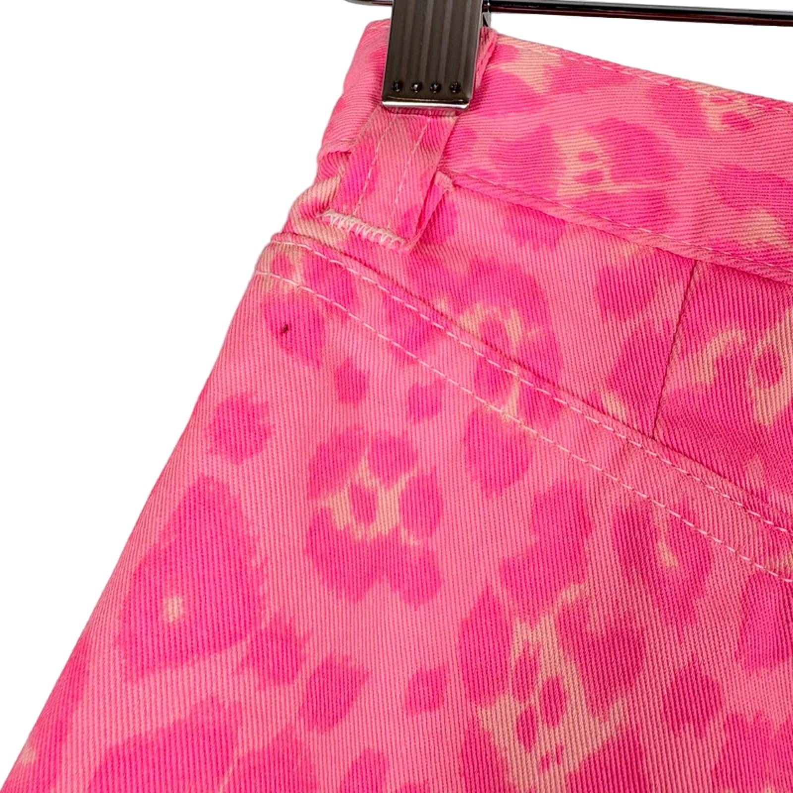 Close-up of a pink leopard print fabric with a metal clip on a white background