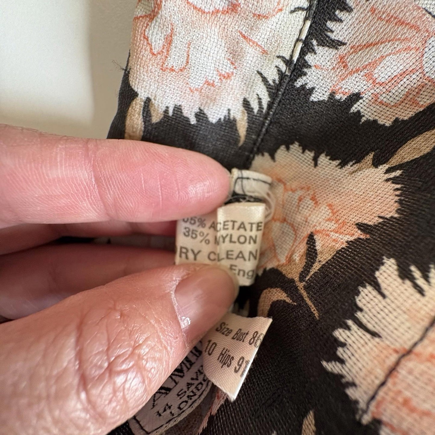 Close-up of a floral fabric with a label held by a hand