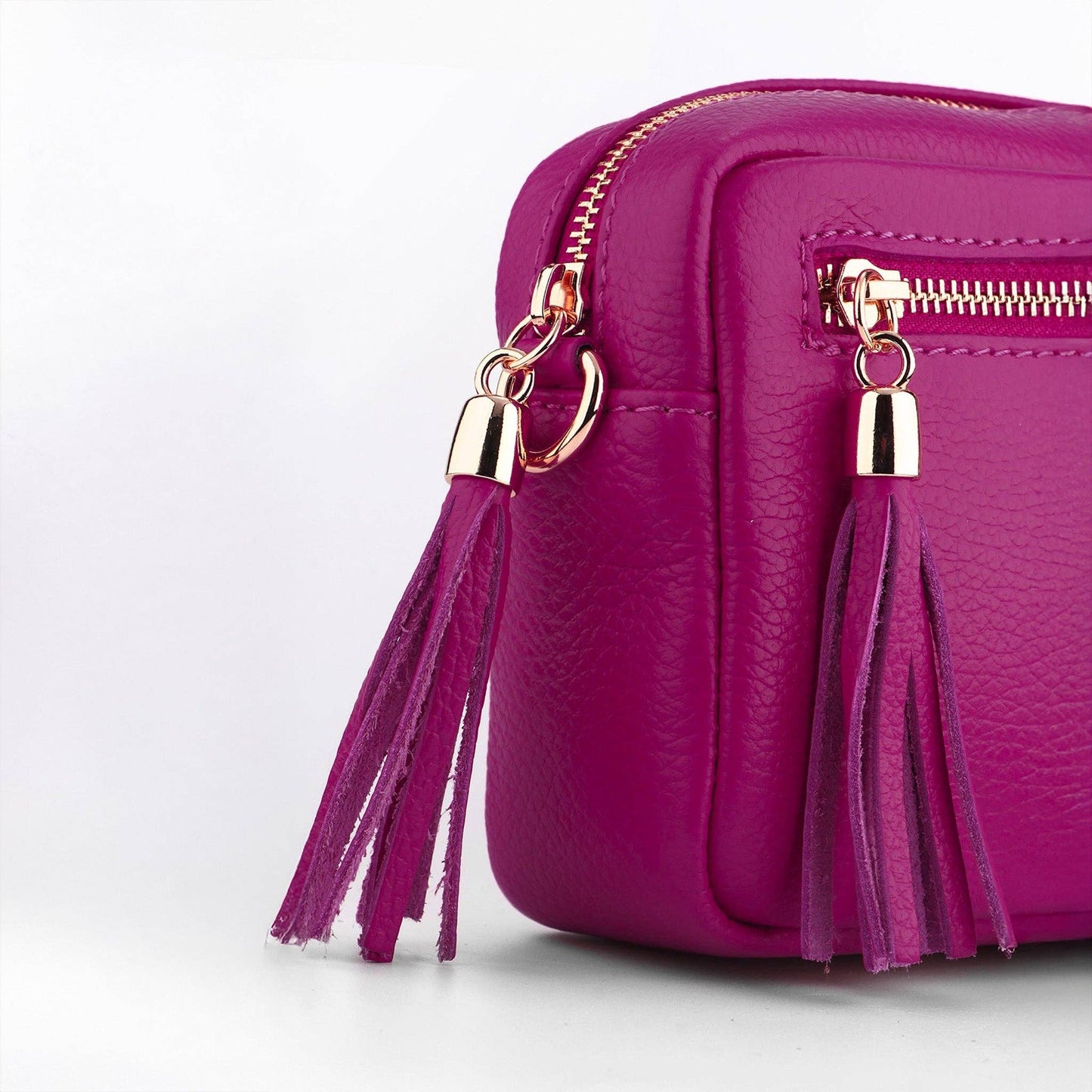 Purple handbag with gold zippers and tassels on a white background