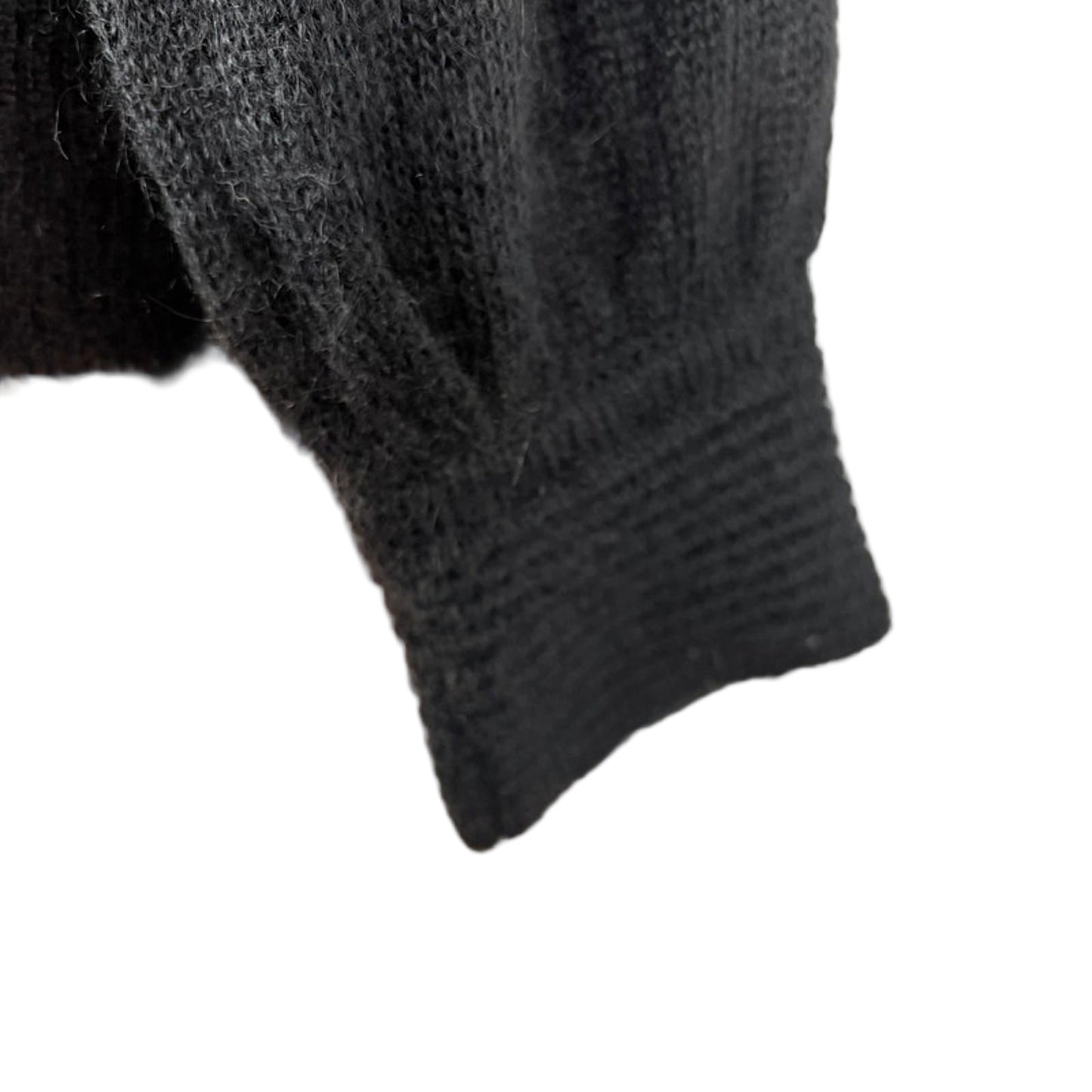 Close-up of a black knitted sweater sleeve on a mannequin arm.