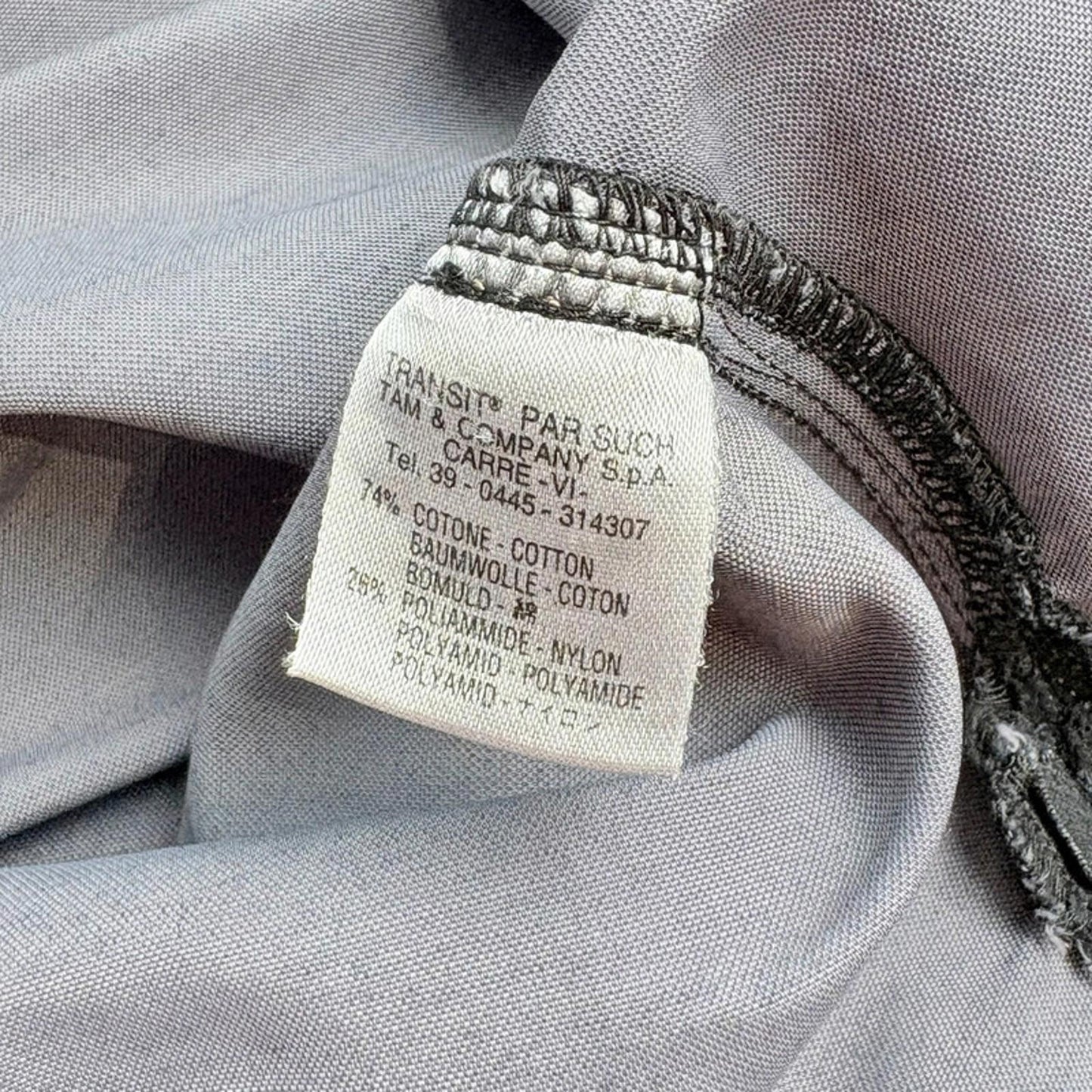 Fabric label with text and material details on a gray fabric background