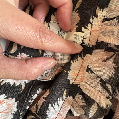 Fabric with a floral pattern and a visible label held by a hand.