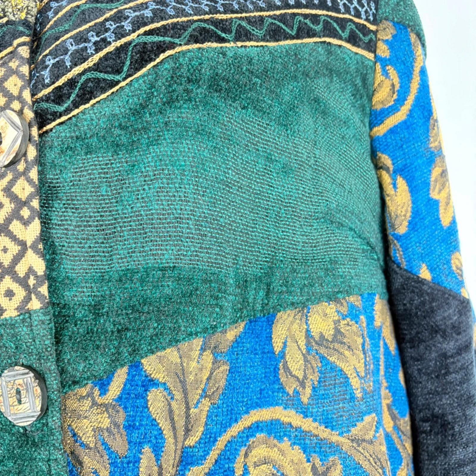 Close-up of a fabric with green, blue, and gold patterns on a white background