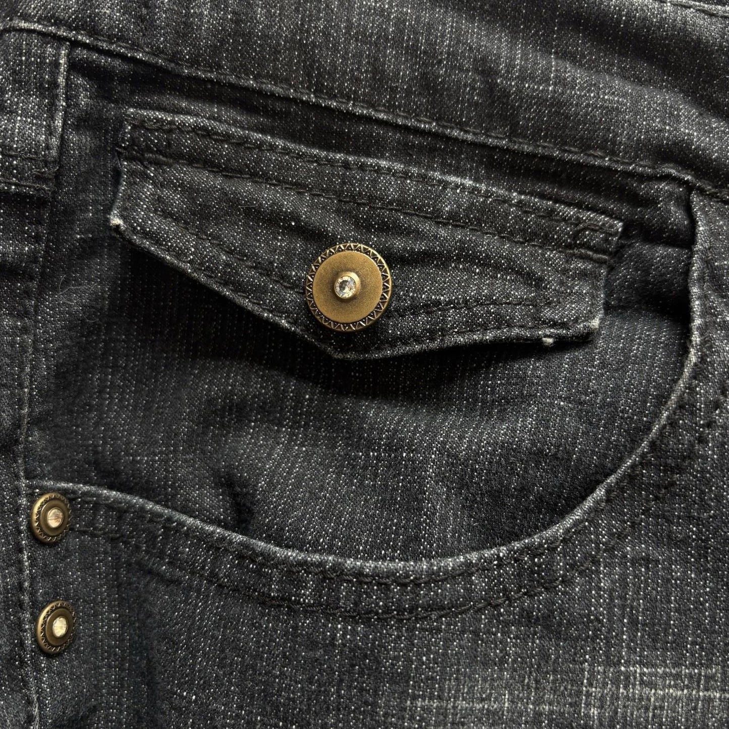 Close-up of black denim fabric with gold buttons