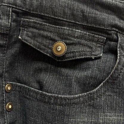 Close-up of black denim fabric with gold buttons