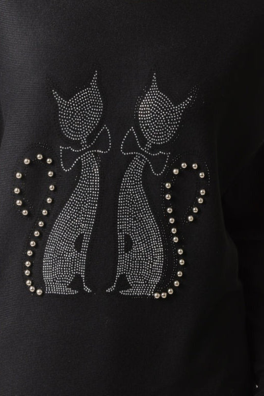 Black sweater with rhinestone cat designs on a dark background