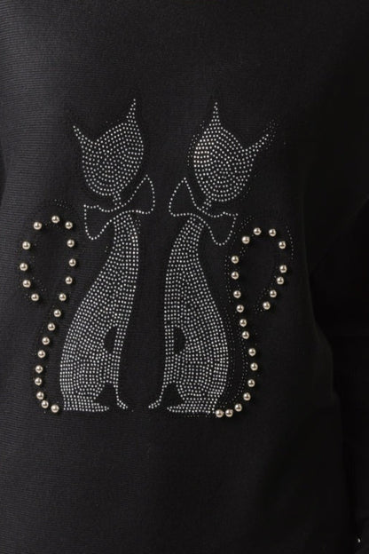 Black sweater with rhinestone cat designs on a dark background