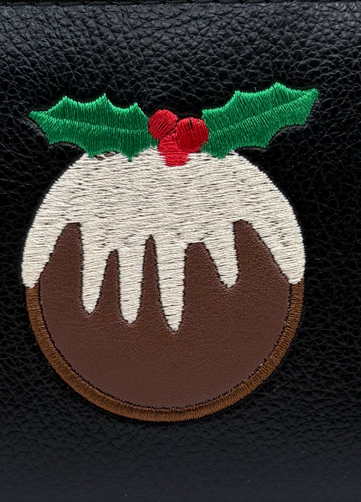 Embroidered Christmas pudding patch with holly on a black background