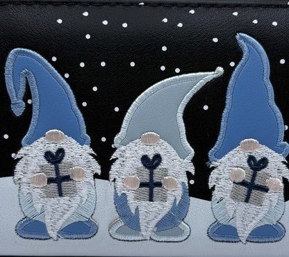 Three embroidered gnomes with blue hats and boots on a black background with white dots.