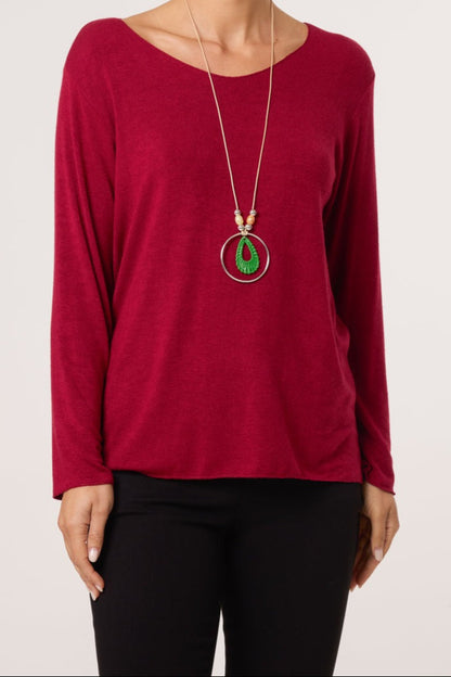 Red long-sleeve top worn by a person with a necklace featuring green and red elements on a white background