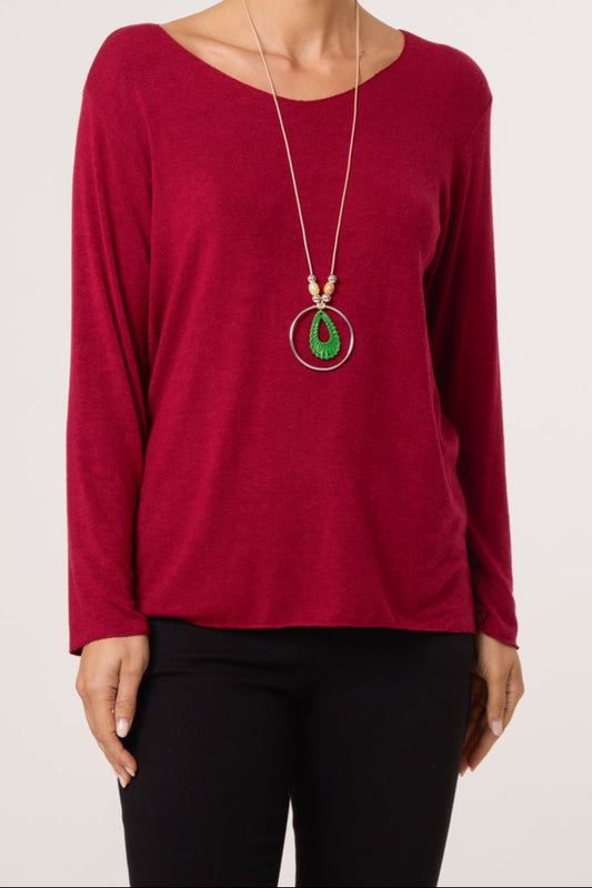 Red long-sleeve top worn by a person with a necklace featuring green and red elements on a white background