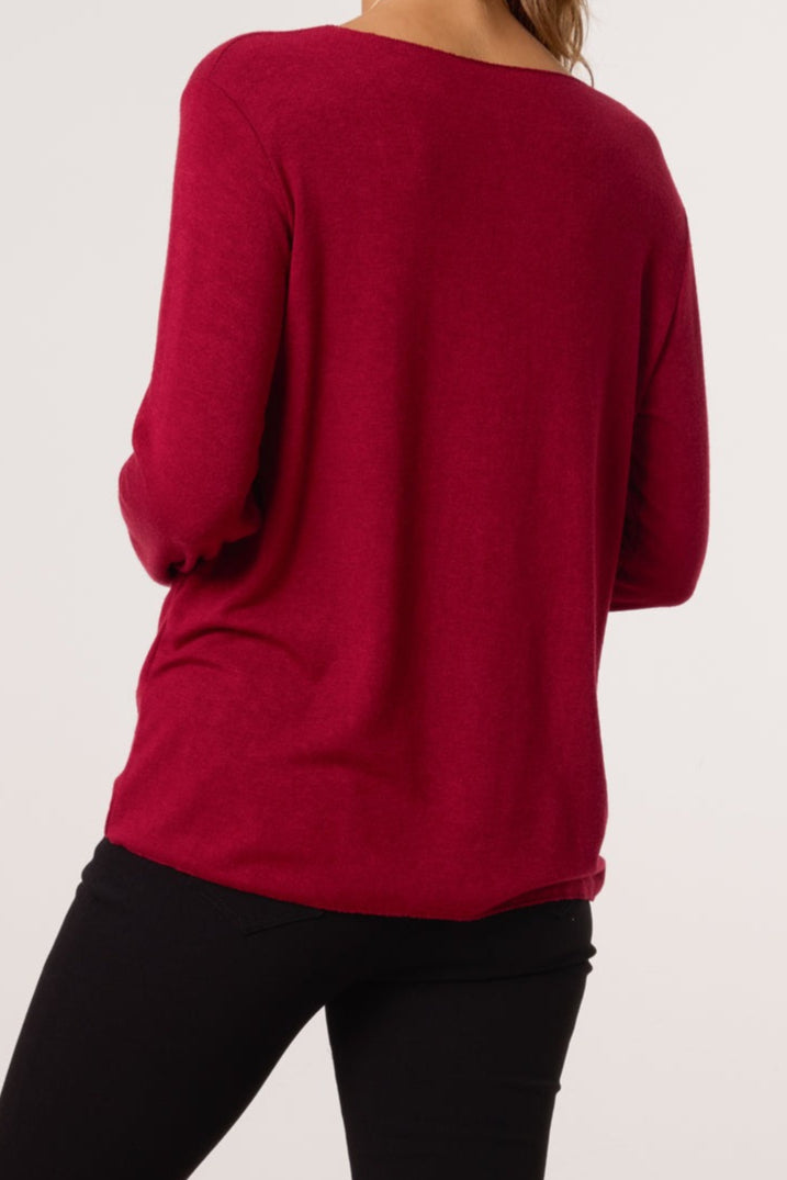 Red long-sleeve top worn by a person on a white background