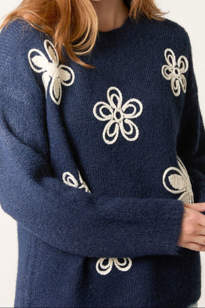 Navy blue sweater with white floral patterns on a plain background