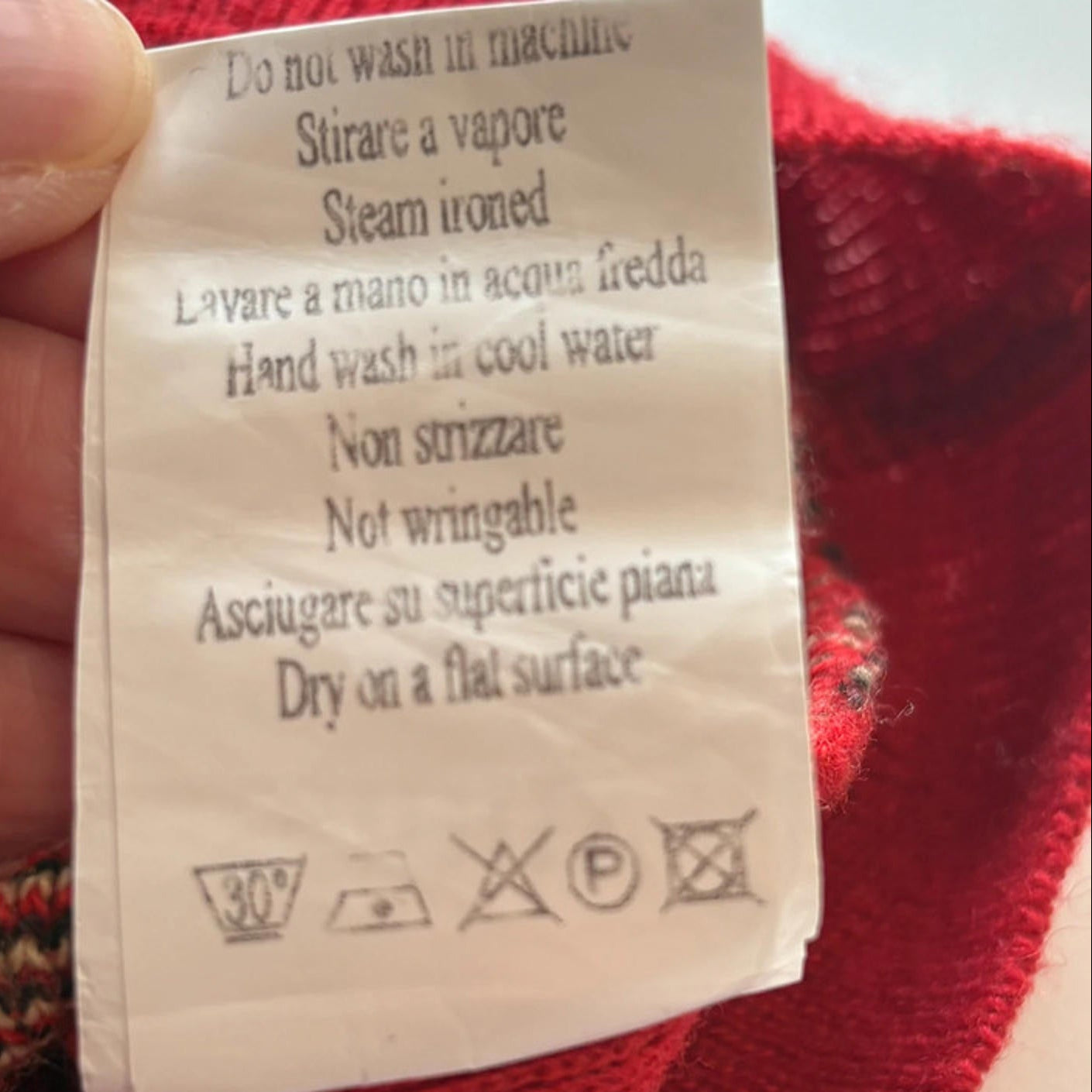 Clothing label with care instructions on a red fabric background