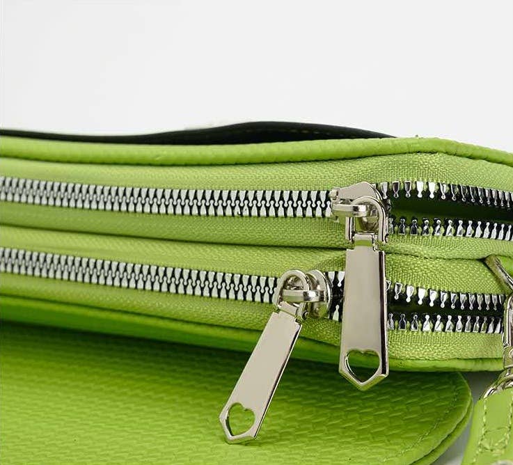 Close-up of a green bag with multiple zippers on a white background