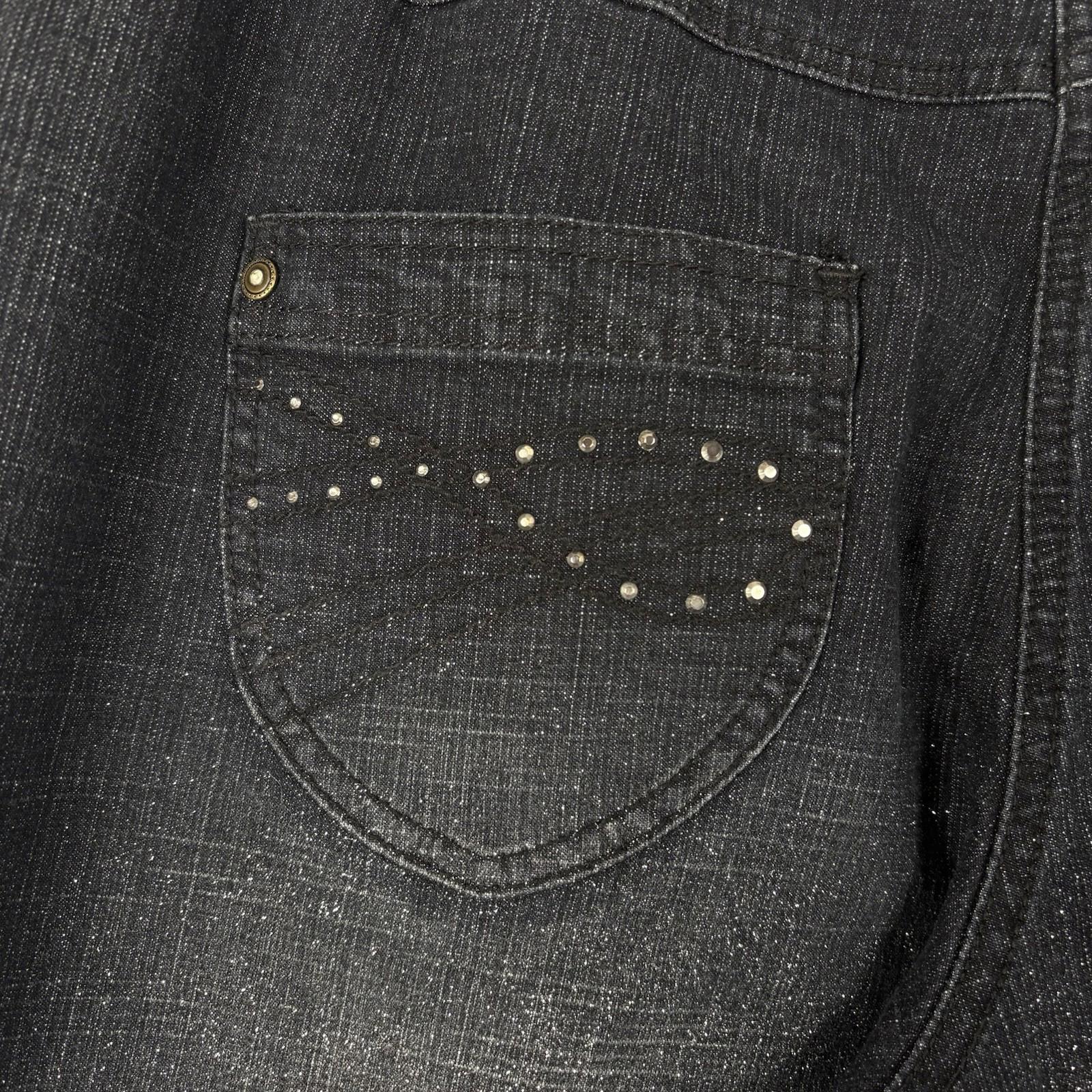 Close-up of a dark denim shirt with a pocket featuring decorative studs.