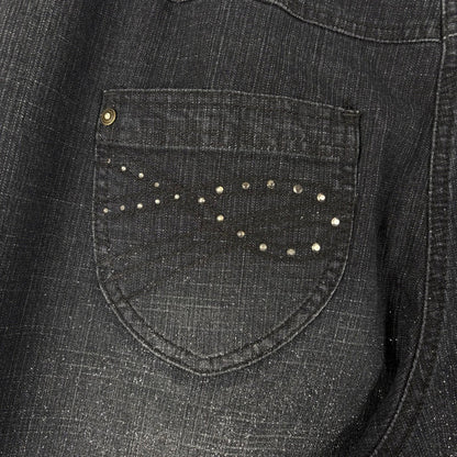 Close-up of a dark denim shirt with a pocket featuring decorative studs.