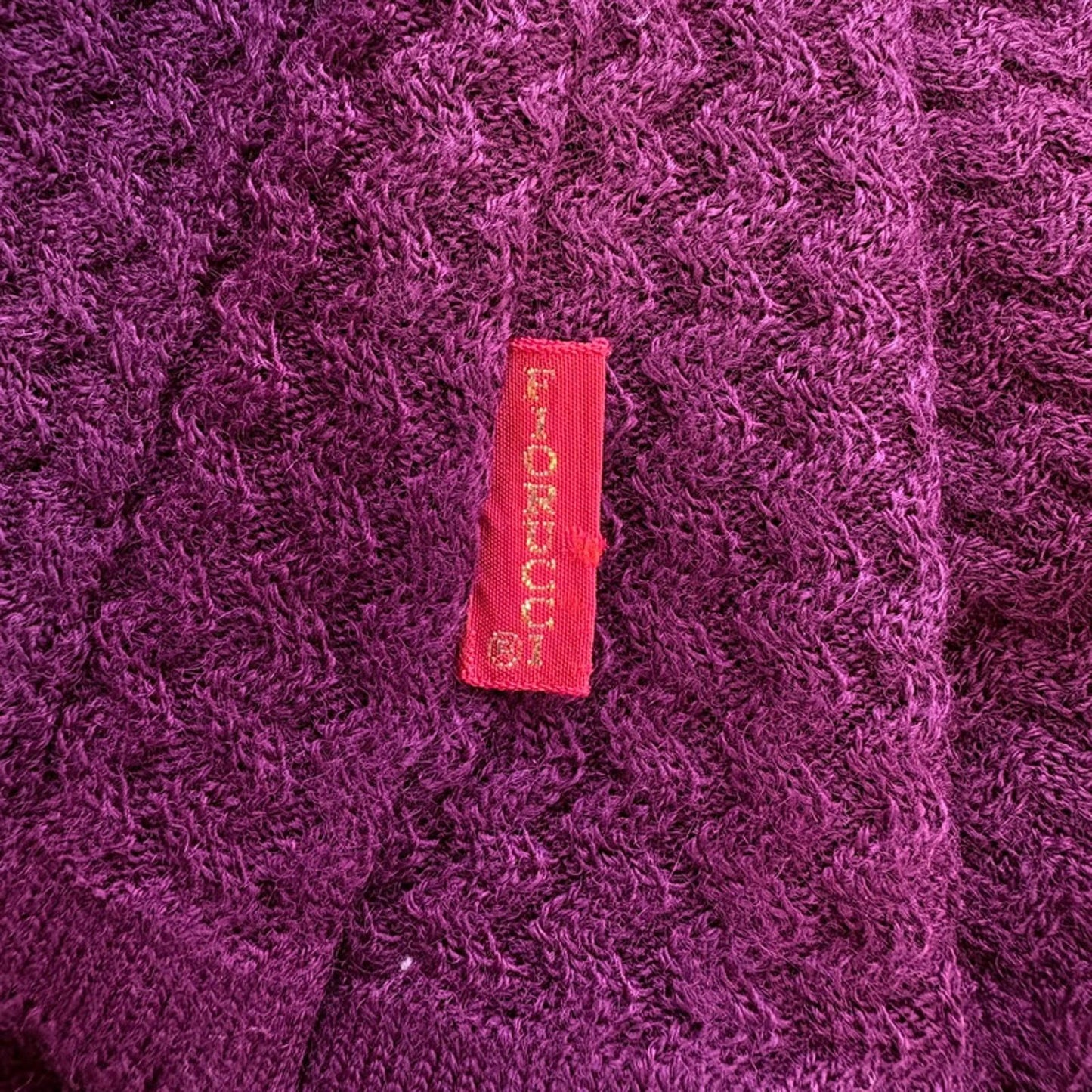Close-up of a textured purple fabric with a red label featuring text.