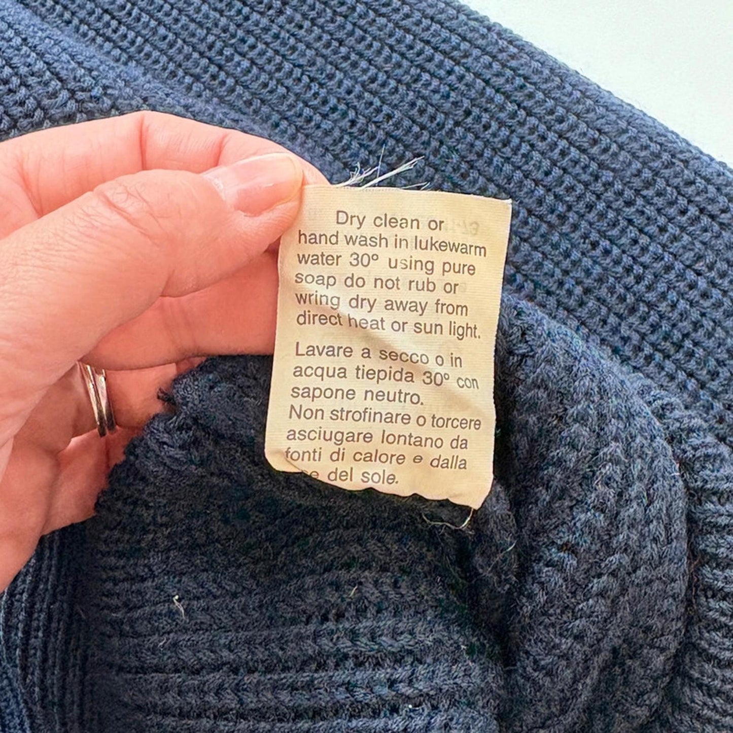 Hand holding a care label on a blue textured fabric