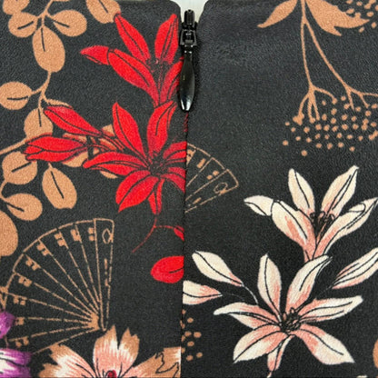 Close-up of floral-patterned fabric with a zipper, featuring red, pink, and beige flowers on a black background.