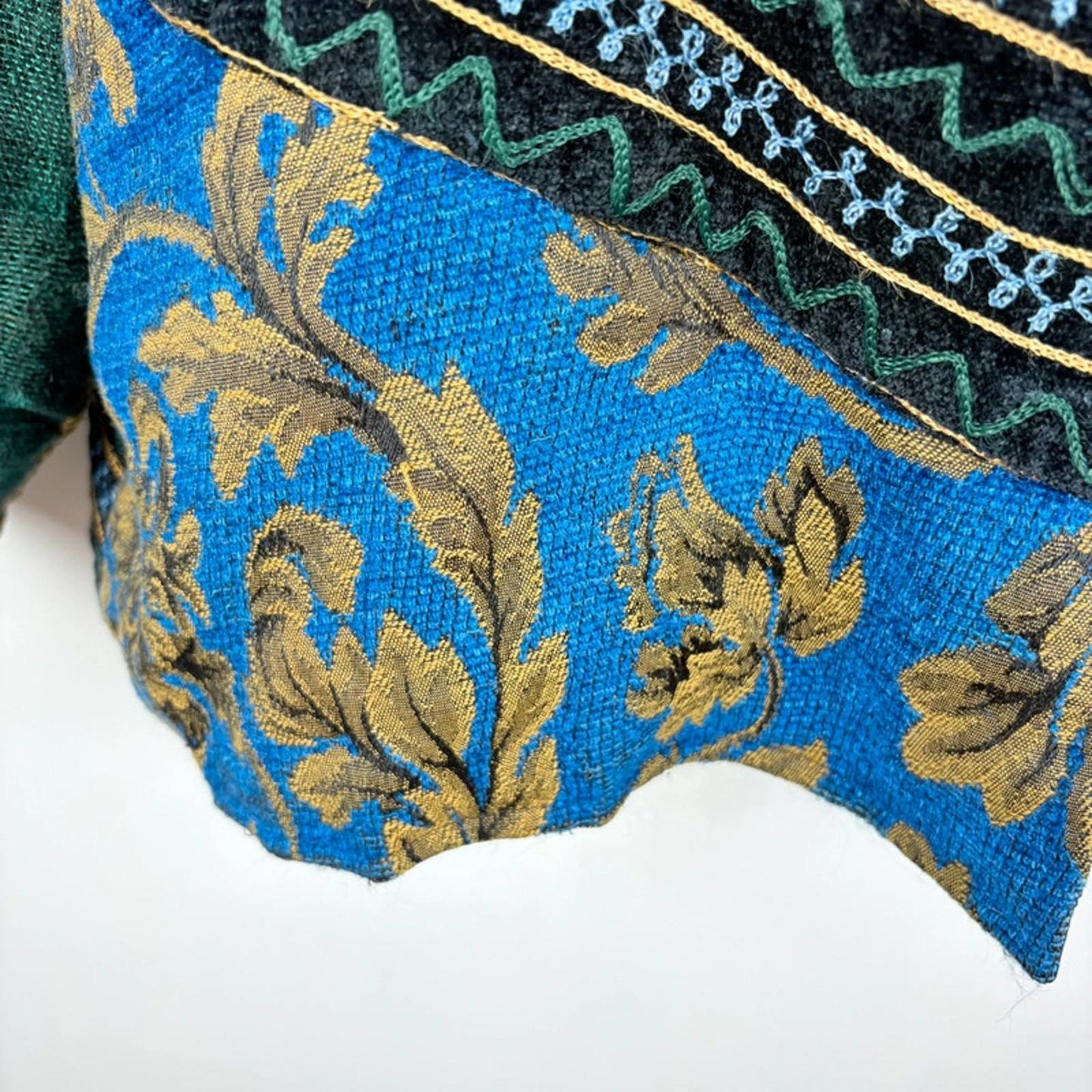 Close-up of a blue fabric with gold embroidery on a white background