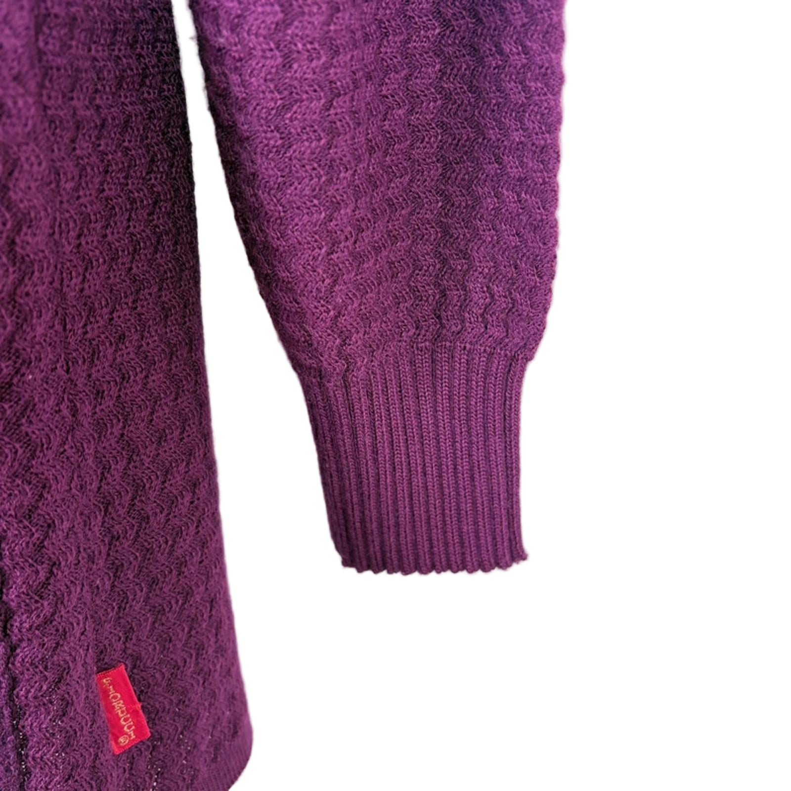Close-up of a purple sweater with cable knit pattern on a white background