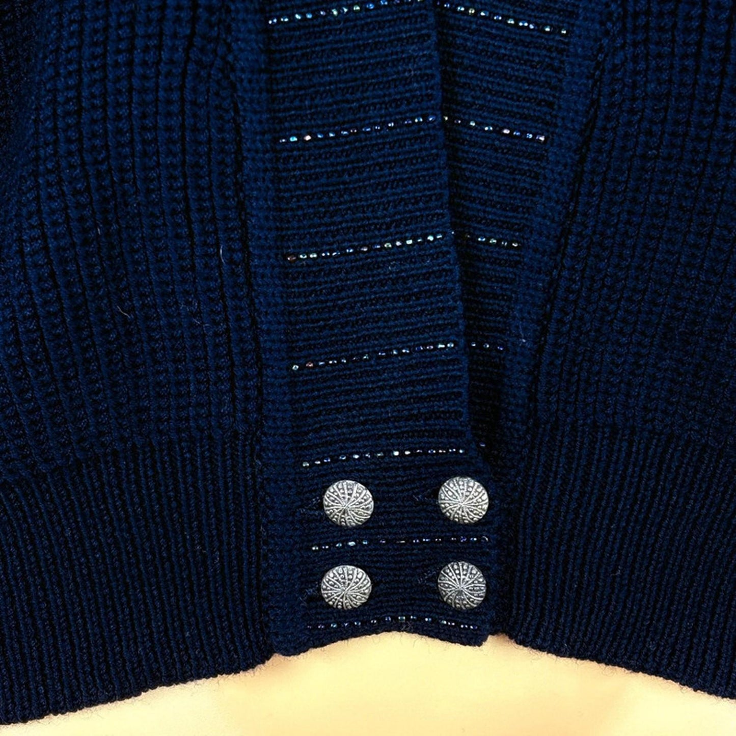 Close-up of a navy blue cardigan with button details on a beige background