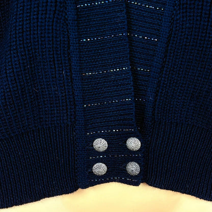 Close-up of a navy blue cardigan with button details on a beige background